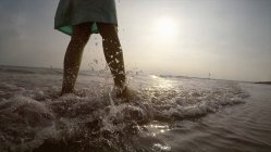 Pernas de mulher na costa andando no oceano — Fotografia de Stock