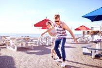Couple using skateboard on promenade — Stock Photo