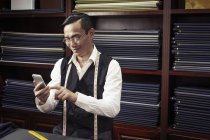 Tailor texting on cellphone in tailors shop — Stock Photo