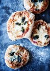 Fresh baked pizzas with herbs and flour on kitchen counter — Stock Photo