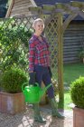 Woman carrying watering can in garden — Stock Photo