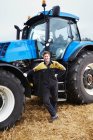 Agriculteur debout par tracteur dans le champ — Photo de stock