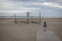 Девушка на пляже смотрит на океан — стоковое фото