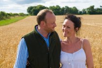 Mid adult couple walking through field, smiling — Stock Photo