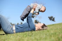 Femme jouant avec bébé dans l'herbe — Photo de stock