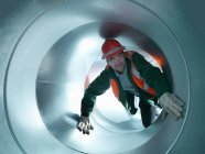 Portrait of workman in stainless steel air pipe of building site — Stock Photo