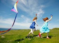 2 young girls running with kites — Stock Photo