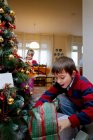 Junge begutachtet Weihnachtsgeschenke — Stockfoto