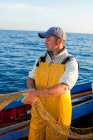 Рыбак тянет сеть на лодке — стоковое фото