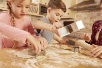 Девочки и мальчик выпечка звездной формы выпечки за кухонным столом — стоковое фото