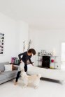 Mujer jugando con perro en la sala de estar - foto de stock