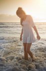 Женщина, гуляющая в воде на пляже — стоковое фото