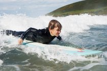 Jeune garçon surfant sur une vague — Photo de stock