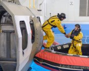 Trabajadores petroleros offshore entrenándose en escape del simulador de helicópteros en instalaciones de entrenamiento en piscinas - foto de stock