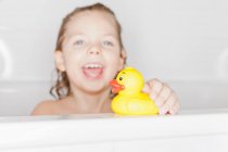Girl playing with rubber duck in bath — Stock Photo