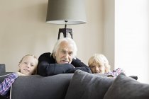 Портрет дедушки и внуков, опирающихся на диван — стоковое фото