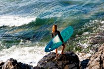 Mujer de pie con una tabla de surf - foto de stock