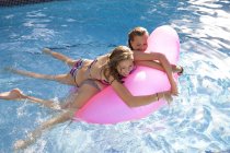 Two teenage girls holding air bed in swimming pool — Stock Photo