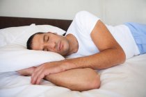Мужчина спит на кровати дома — стоковое фото