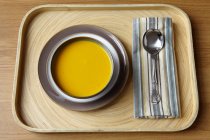 Tray with bowl of cream soup and spoon on cloth napkin — Stock Photo