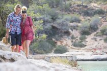Pareja paseando por las rocas por mar, Mallorca, España - foto de stock