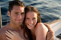 Молода пара на вітрильному човні, посміхаючись — стокове фото