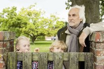 Дедушка и внуки у деревянных ворот — стоковое фото