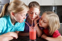 Girls drinking fruit juice with straws — Stock Photo