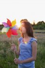 Menina soprando moinho de vento brinquedo ao pôr do sol — Fotografia de Stock