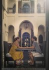 Vista lateral de la pareja joven en la mesa cara a cara cogidos de la mano, Marrakech, Marruecos - foto de stock