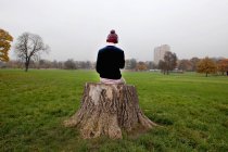 Man sitting on tree stump listening to music — Stock Photo