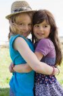 Lächelnde Mädchen, die sich draußen umarmen — Stockfoto