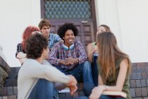 Estudiantes sentados juntos en el campus - foto de stock