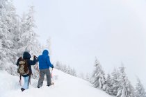 Rear view of father and son snowshoeing on hillside — Stock Photo
