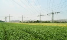 Linhas de energia da fábrica sobre os campos — Fotografia de Stock