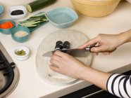 Image recadrée de femme coupe sushi à la table — Photo de stock