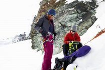 Montañeros preparando equipo en montaña cubierta de nieve, Saas Fee, Suiza - foto de stock