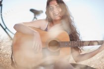 Frau spielt Gitarre im hohen Gras — Stockfoto