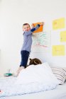 Boy hanging drawing on bedroom wall — Stock Photo