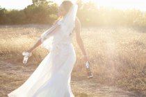Newlywed bride carrying champagne — Stock Photo