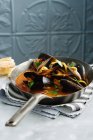 Pot of mussels in tomato sauce on cloth napkin — Stock Photo