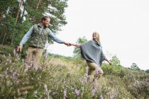Mid adult couple holding hands in meadow — Stock Photo