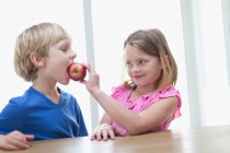 Crianças comendo maçã na cozinha, foco em primeiro plano — Fotografia de Stock