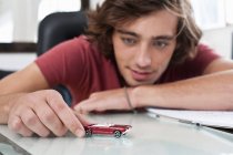 Teenage boy playing with toy car — Stock Photo