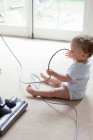 Bébé sur le sol jouant avec le câble hoover — Photo de stock