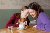 Mulheres sussurrando umas às outras no café — Fotografia de Stock