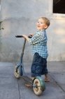 Хлопчик з скутером дивиться на камеру і сміється — стокове фото