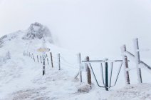 Rural fence obscured by snow and frozen direction sign — Stock Photo