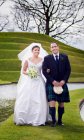 Pareja recién casada caminando en puente cubierto de hierba - foto de stock