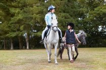 Due ragazze fuori cavalcando pony — Foto stock